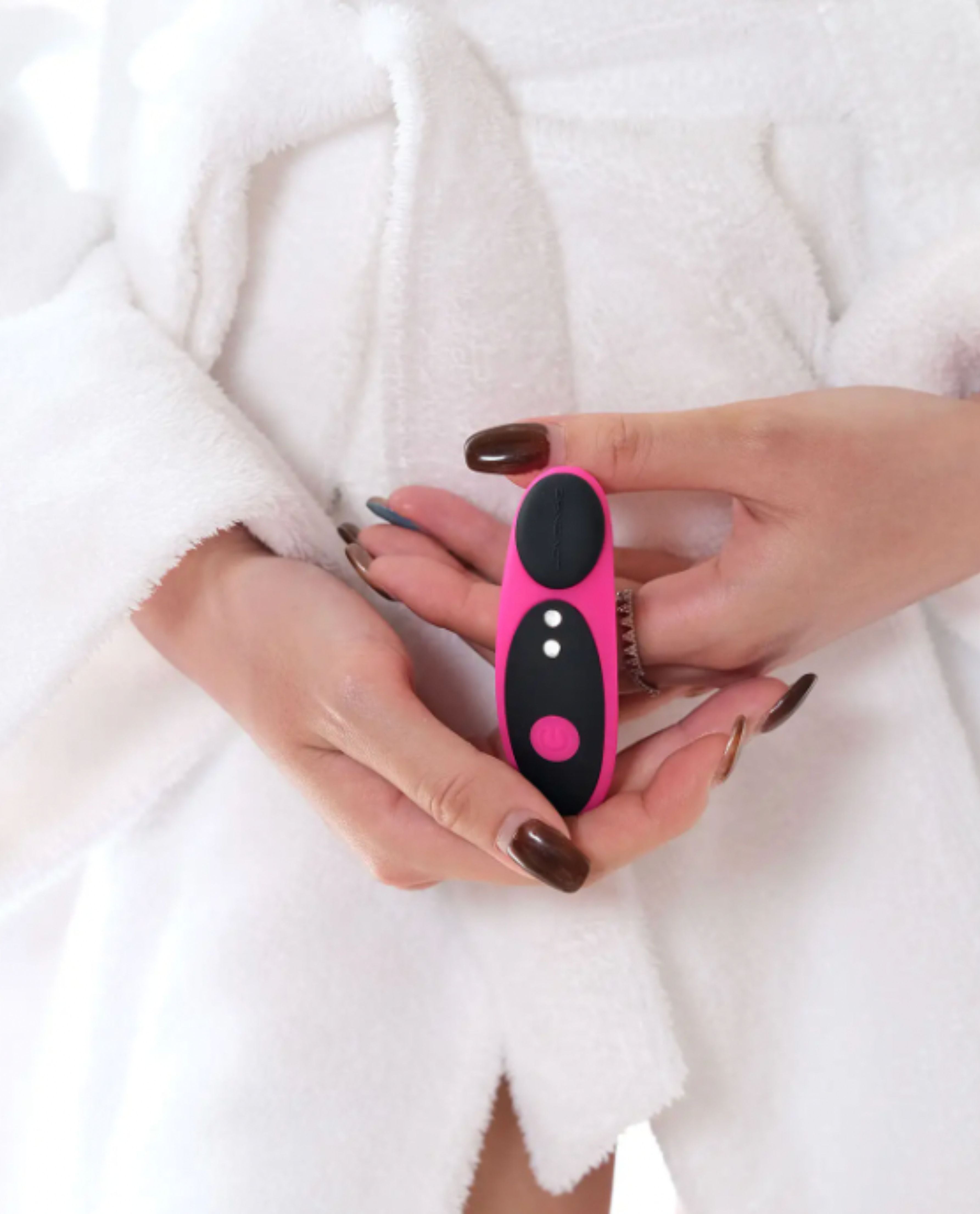 Person holding a the Ferris panty app controlled vibrator by Lovense, against a white robe background