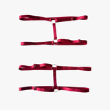 Three red satin belts stacked on a white background