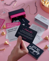 Box of Letz Get Naughty Cards, pink dare card, white truth card, gold necklace and gold wrapped chocolate on the table