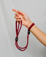 Hand holding a red braided ropes with black clip