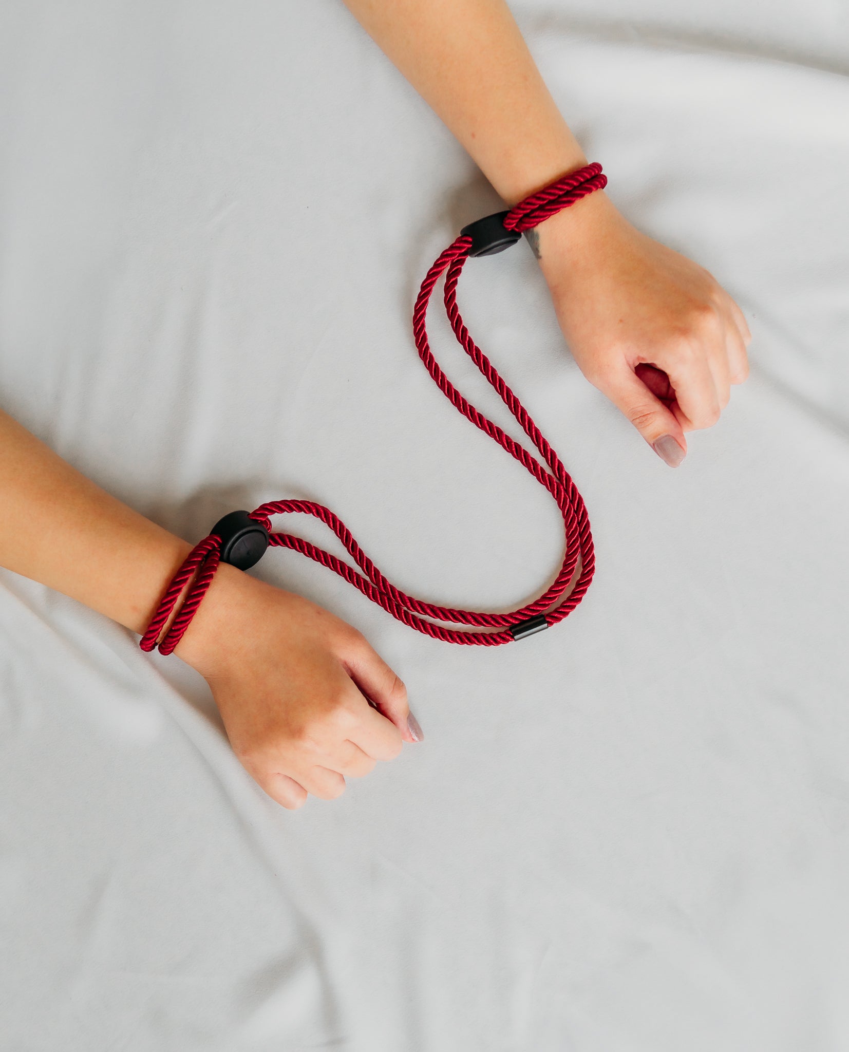 Red rope with black clasps around wrists