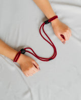 Red rope with black clasps around wrists