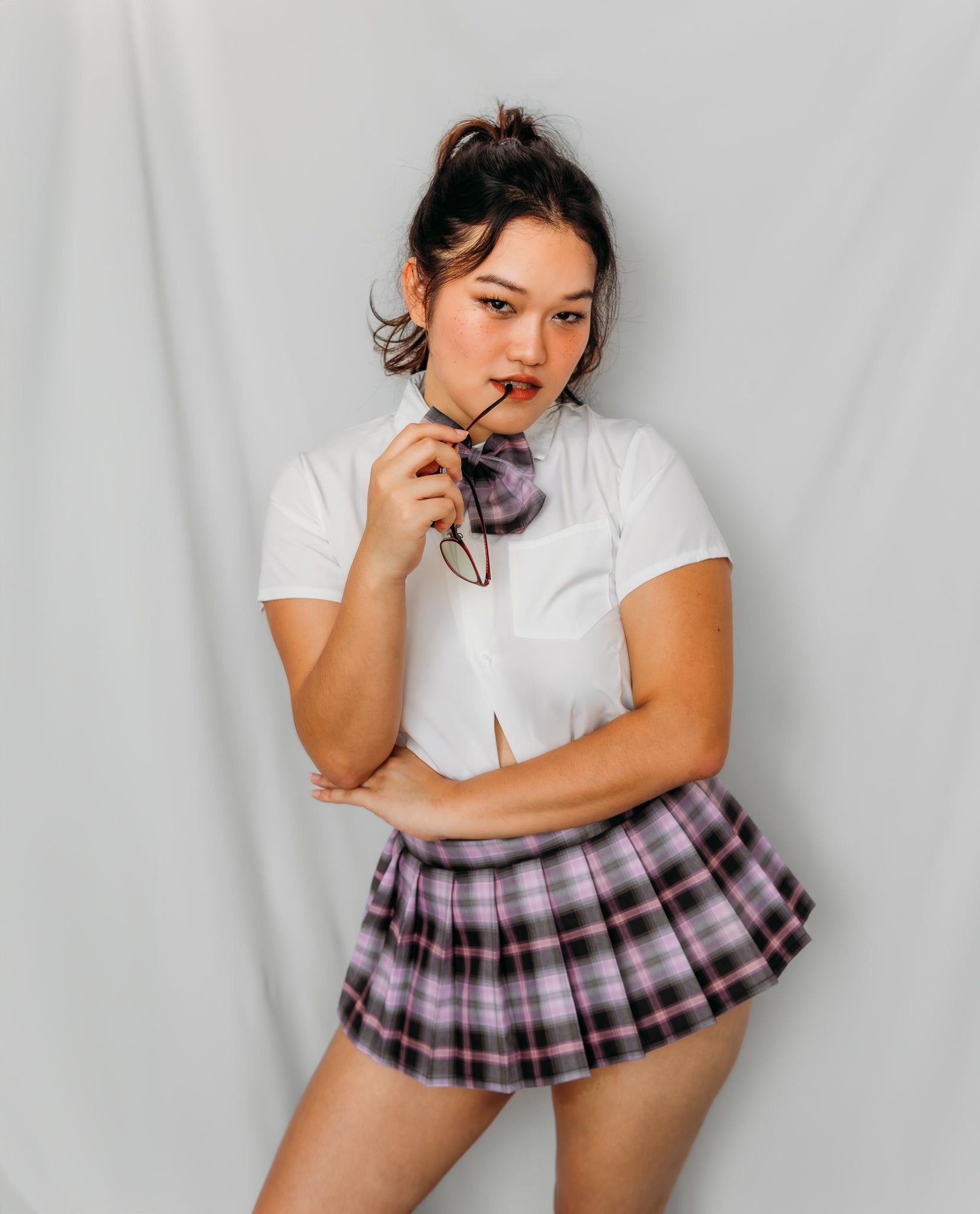 Woman wearing a white crop top and plaid skirt with a bow tie japanese schoolgirl costume