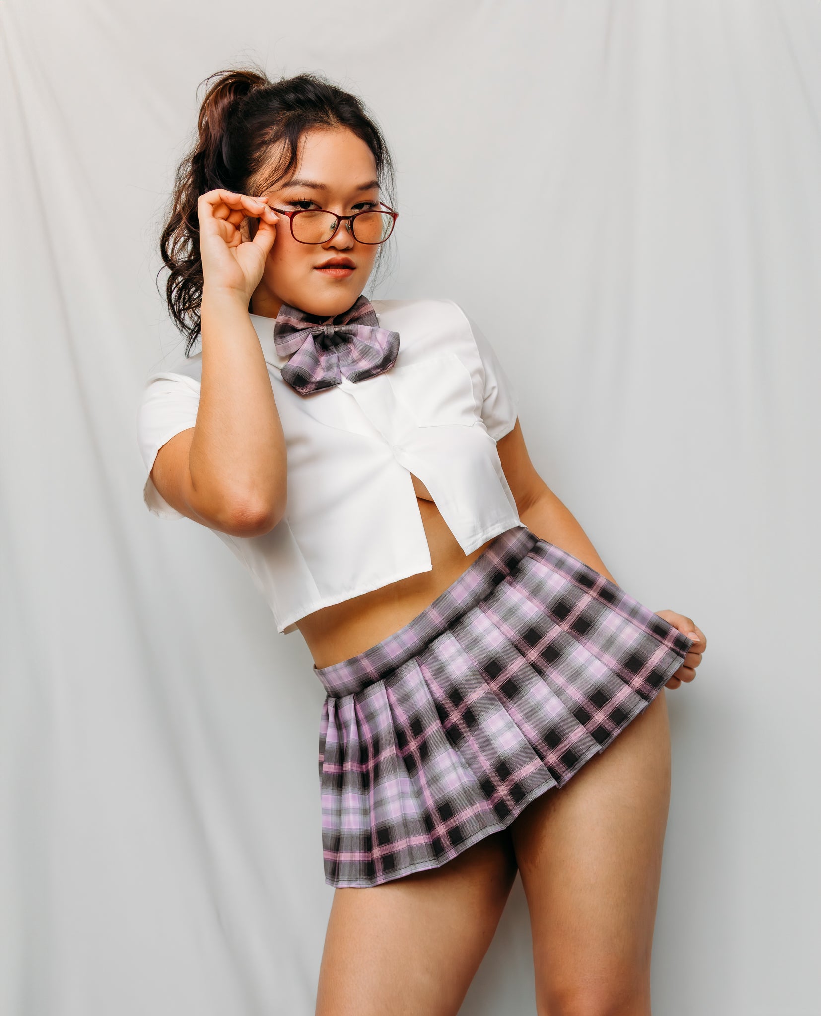 Woman wearing a white crop top and plaid skirt with a bow tie japanese schoolgirl costume