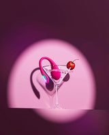 Pink flamingo drink stirrer in a martini glass with a cherry on a pink background and Lush Mini vibrator