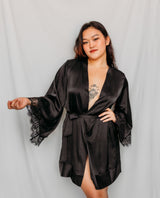 Woman wearing a black satin robe with lace trim