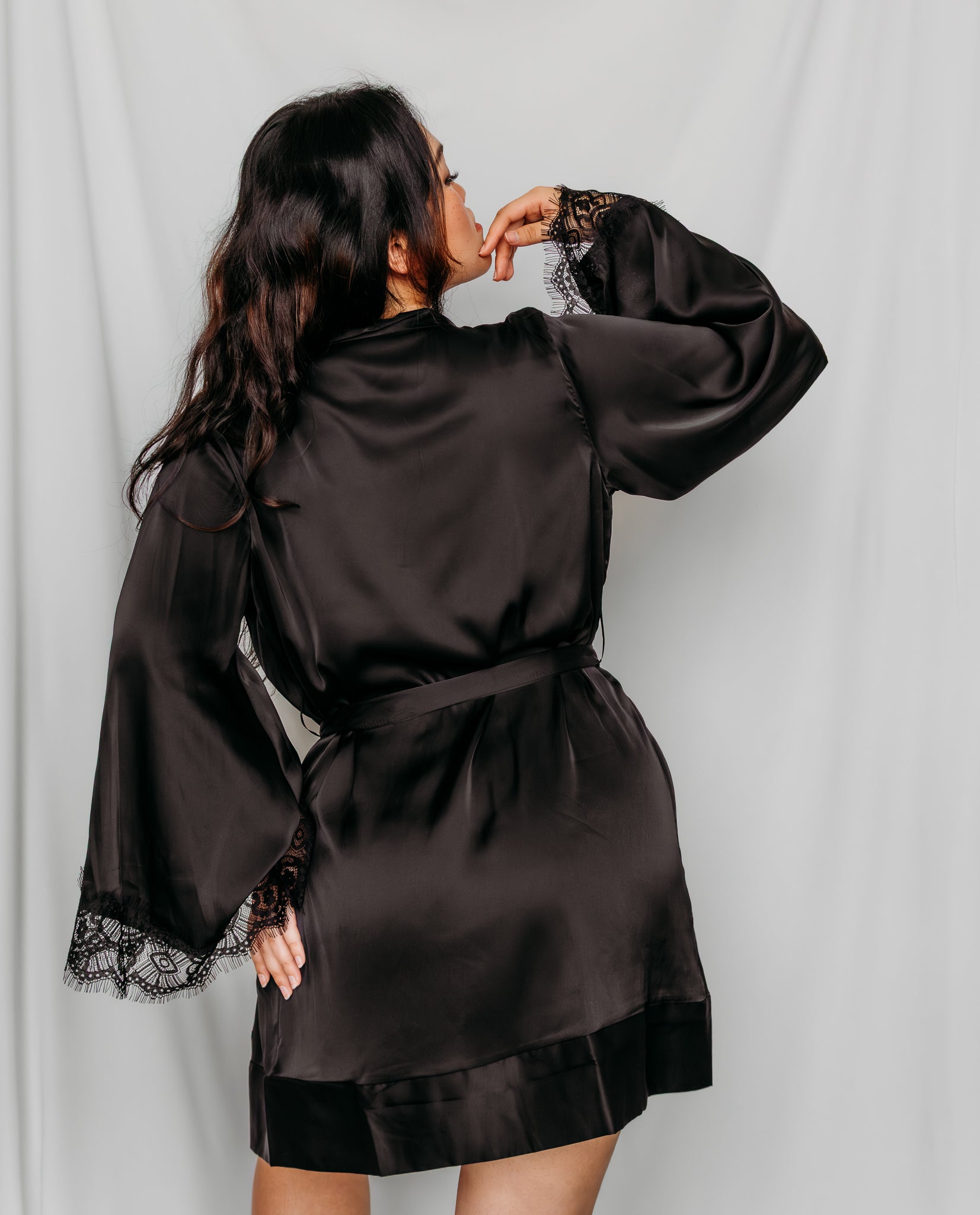 Woman wearing a black satin robe with lace trim