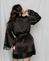 Woman wearing a black satin robe with lace trim
