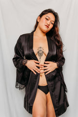 Woman wearing a black satin robe with lace trim