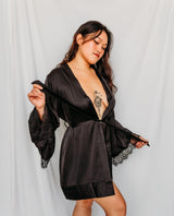 Woman wearing a black satin robe with lace trim