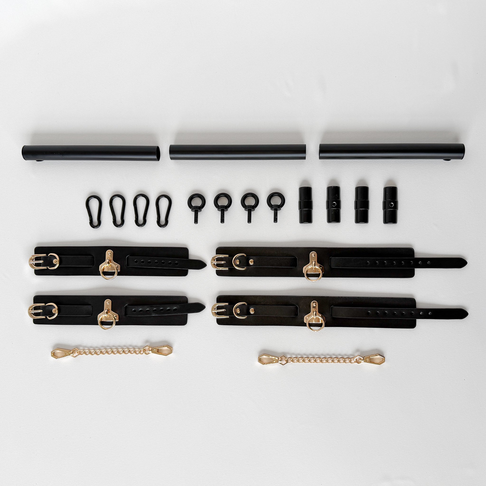 black spreader bar with leather cuffs and connectors flatlay