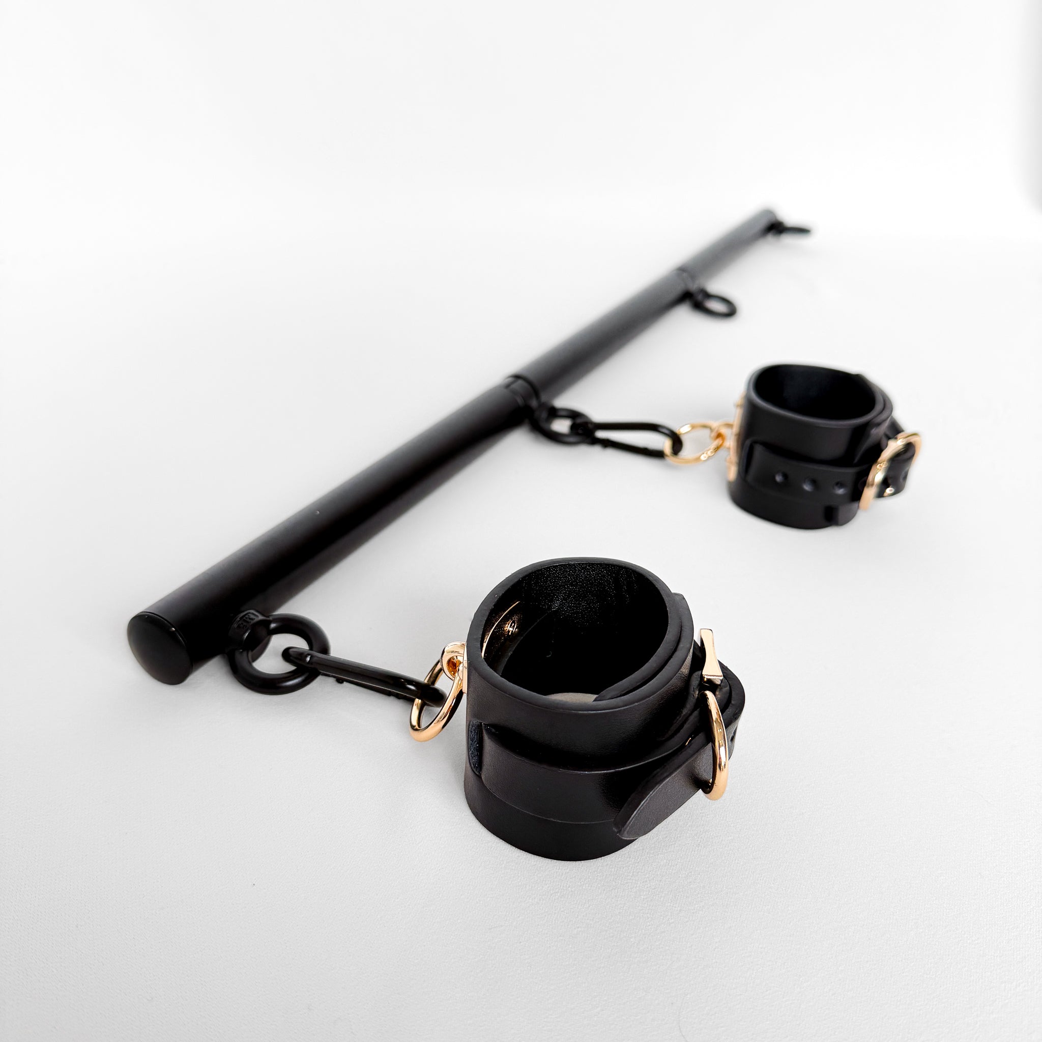Black restraints with gold accents and spreader bar rod