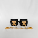 Black leather cuffs with gold hardware and chain