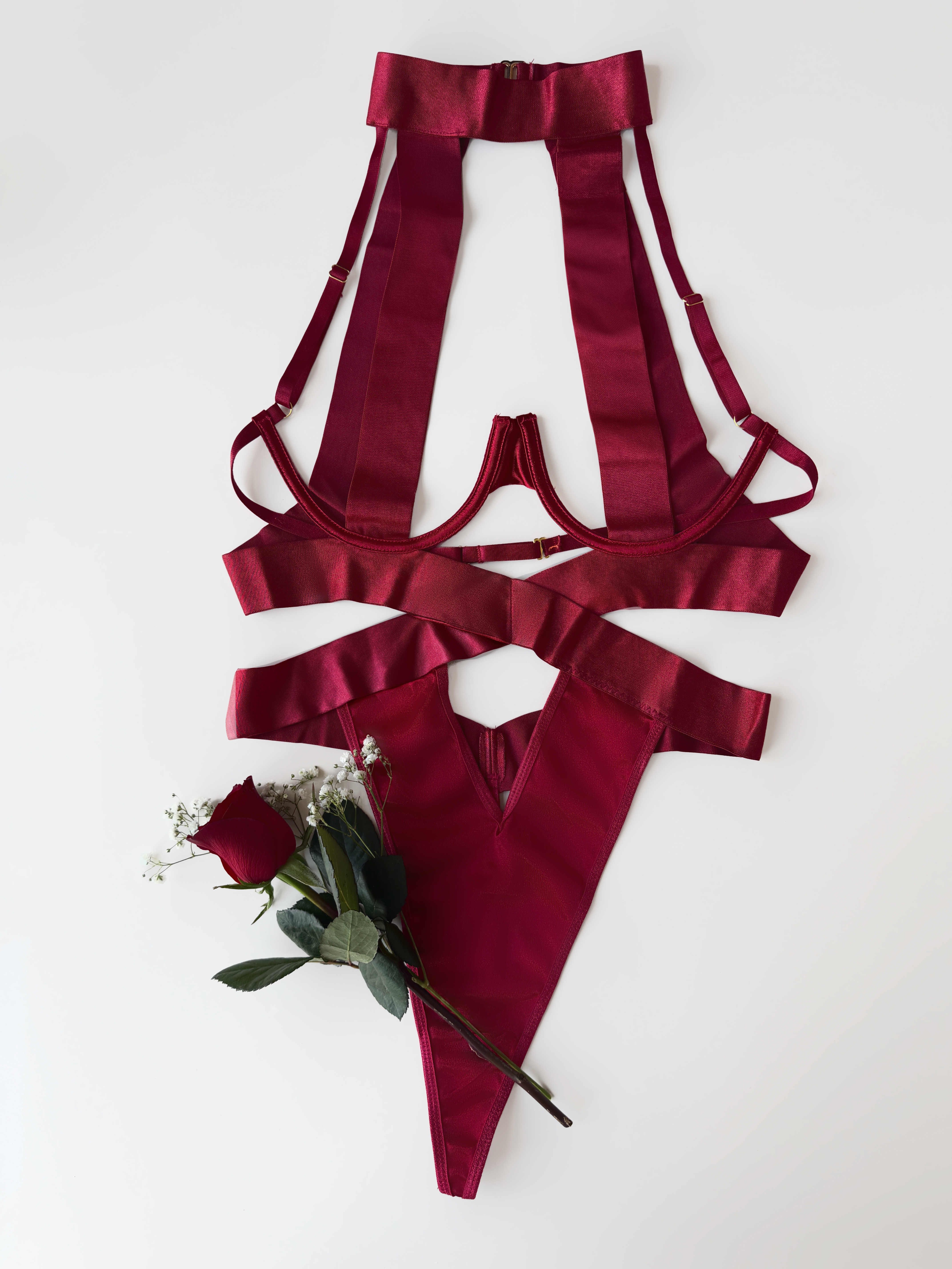 Red satin lingerie set with a single rose on a white background