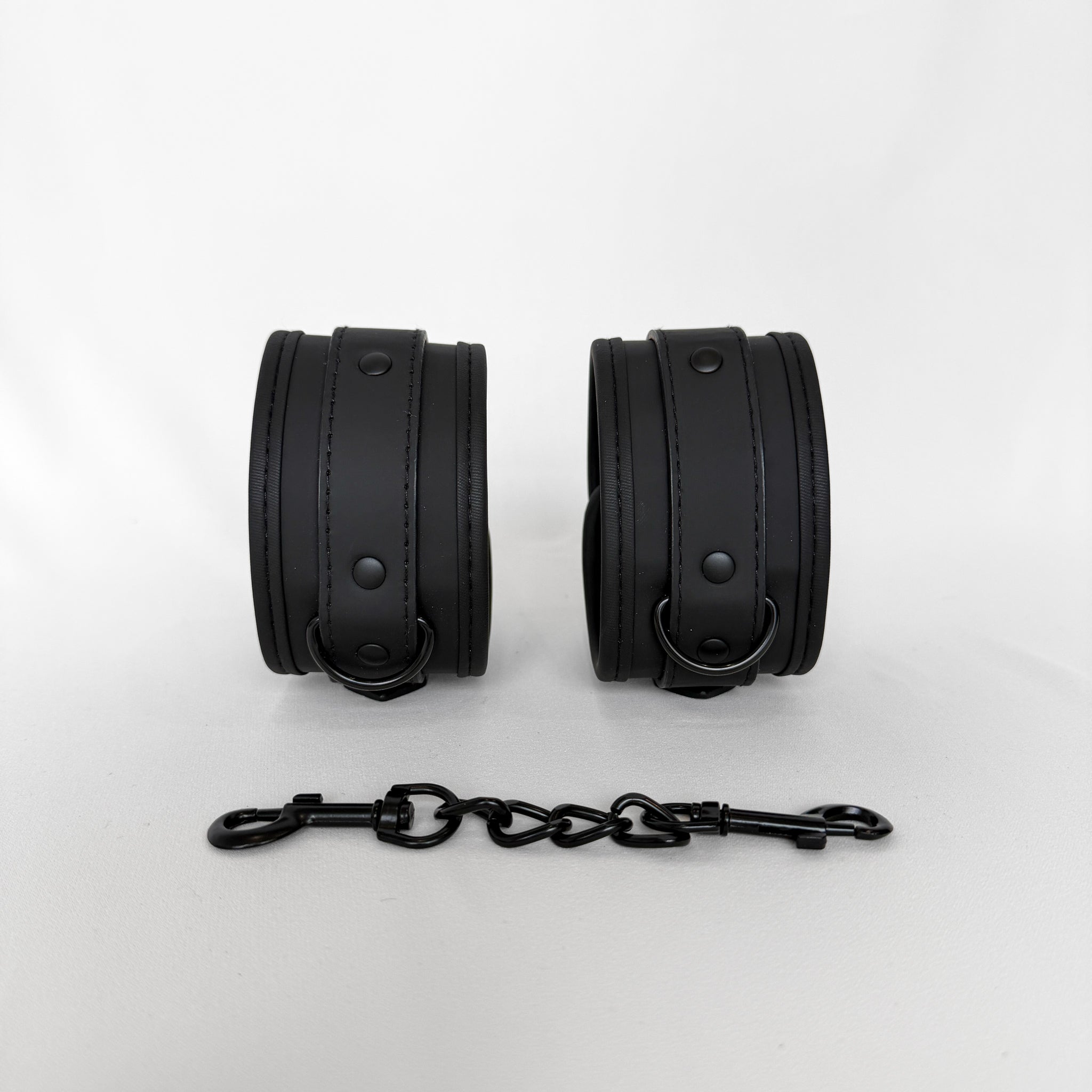 Pair of black leather cuffs with a chain