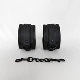 Pair of black leather cuffs with a chain