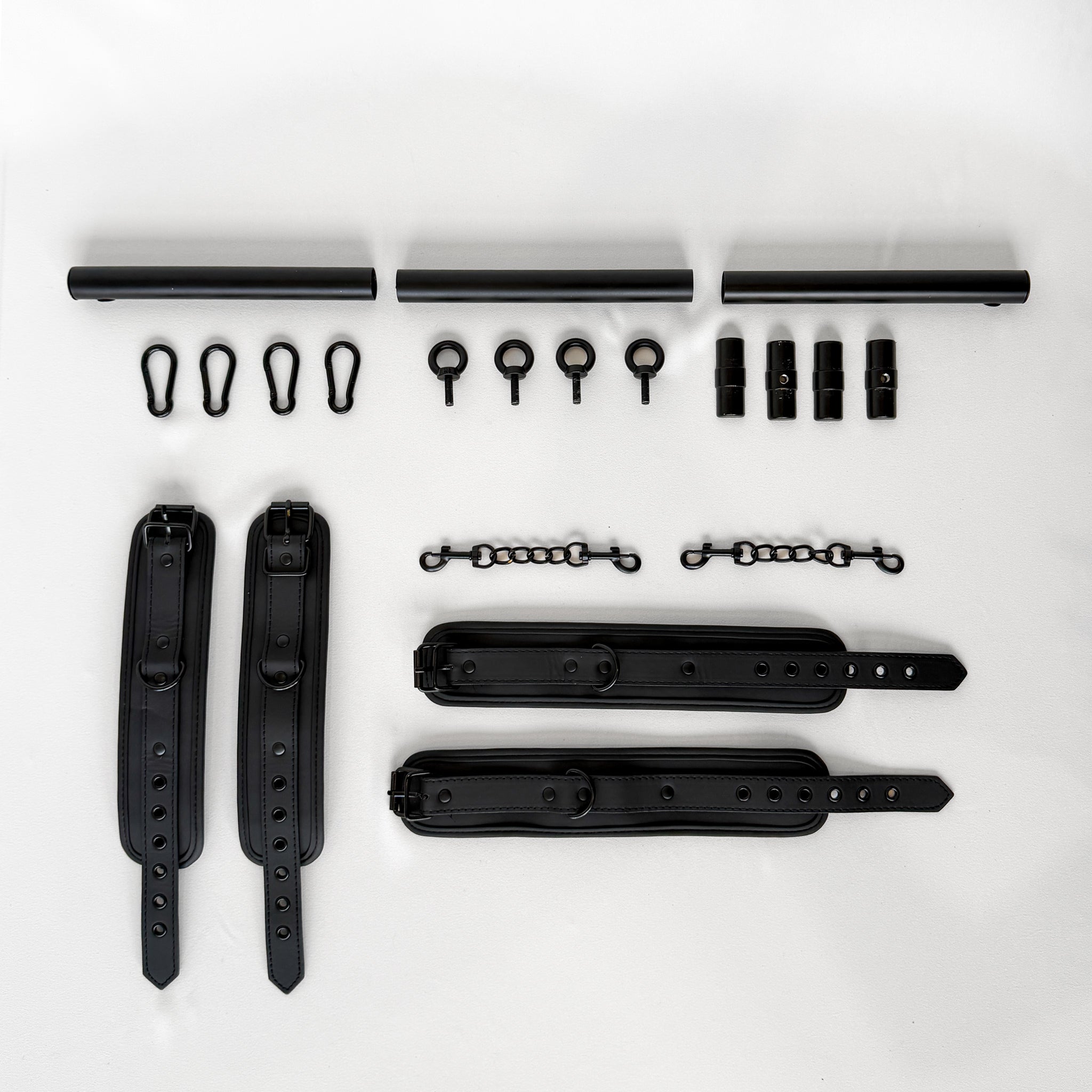 black spreader bar with leather cuffs and connectors flatlay