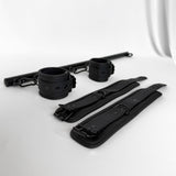 Black bondage spreader bar set including cuffs and straps