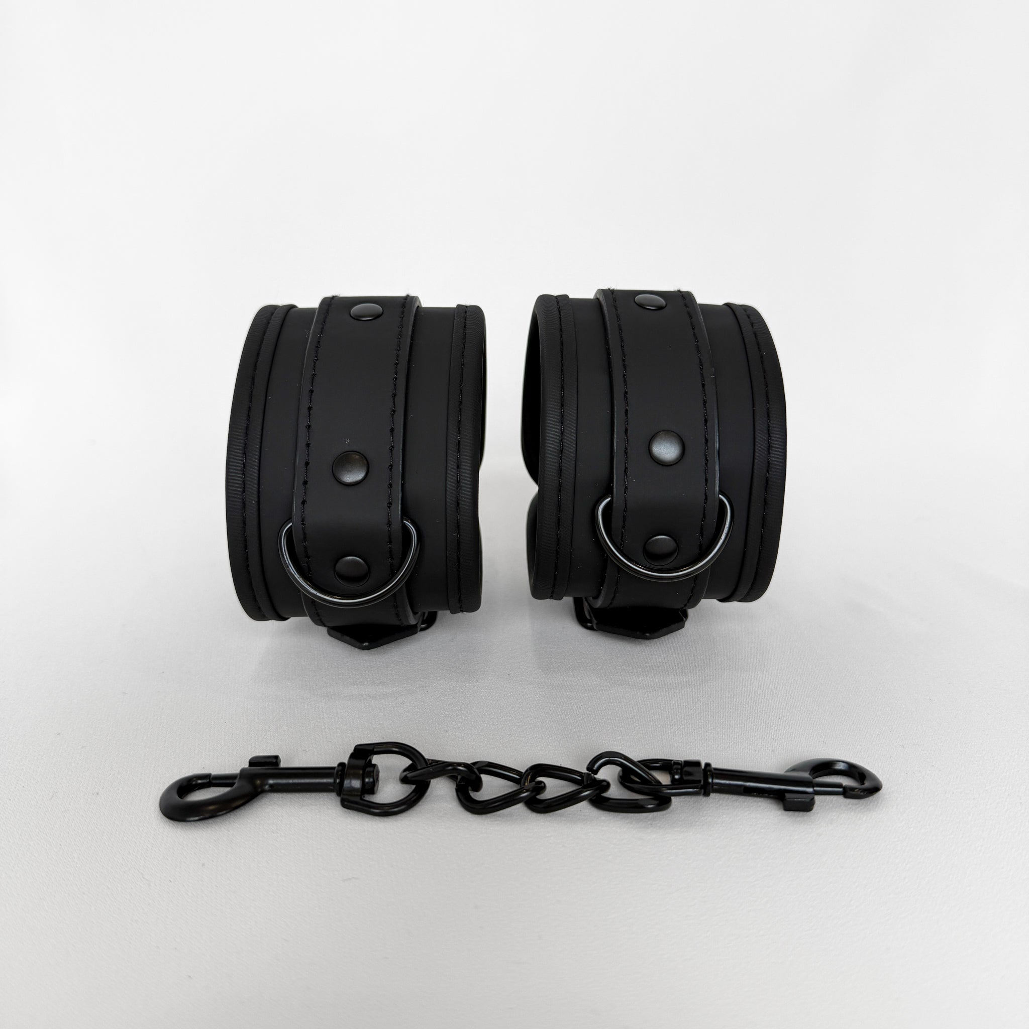 Pair of black leather cuffs with a chain