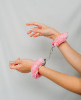 Hands with pink fluffy cuffs and a chain
