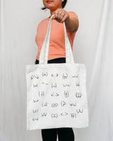 Person holding a white tote bag with black boobs and butt illustration 