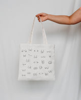 Person holding a white tote bag with black boobs and butt illustration 
