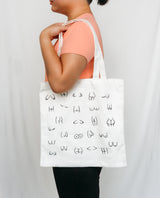 Person holding a white tote bag with black boobs and butt illustration 