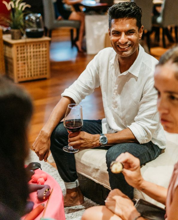 man smiling with a glass of wine in hand